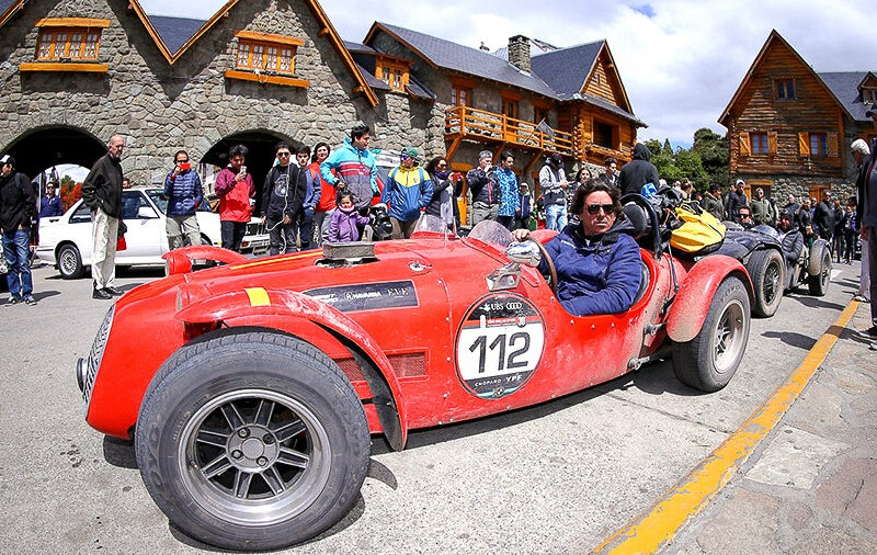 Auto sport clásico rojo de las 1000 Millas Sport rodeado de público en el Centro Cívico de Bariloche