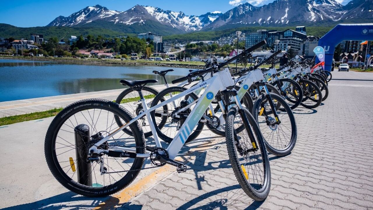 Bicicletas públicas de BiciUshuaia estacionadas en la costanera de Ushuaia con la bahía y los montes Martial de fondo