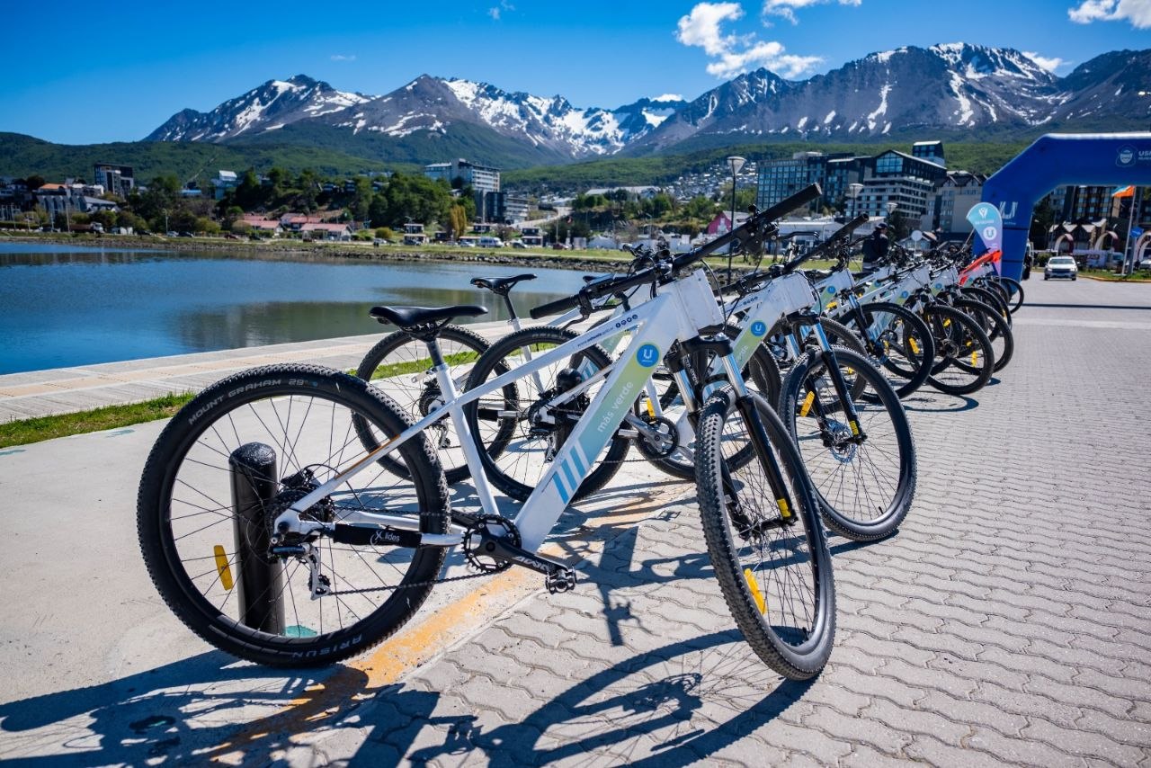 Bicicletas públicas de BiciUshuaia estacionadas en la costanera de Ushuaia con la bahía y los montes Martial de fondo