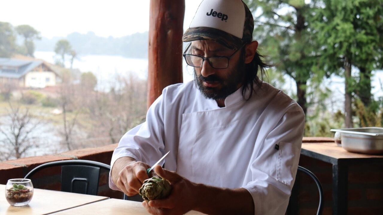 El chef Matías Tesoriero limpia alcauciles en la terraza de Borravino, frente al lago Aluminé en Villa Pehuenia