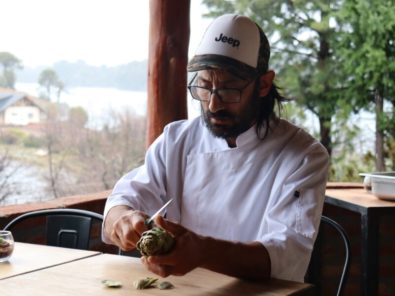 El chef Matías Tesoriero limpia alcauciles en la terraza de Borravino, frente al lago Aluminé en Villa Pehuenia