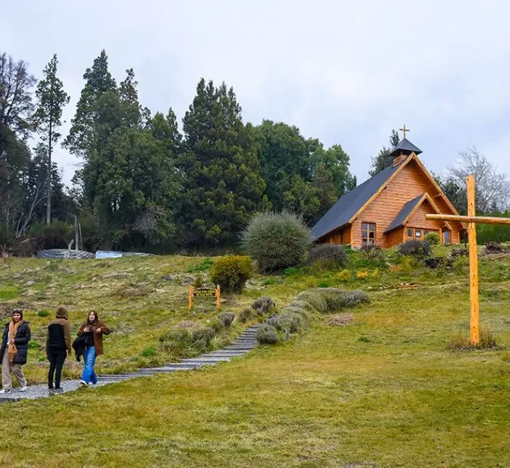 Capilla de madera Nuestra Señora de Traful entre árboles y una cruz de madera, en Villa Traful, Neuquén