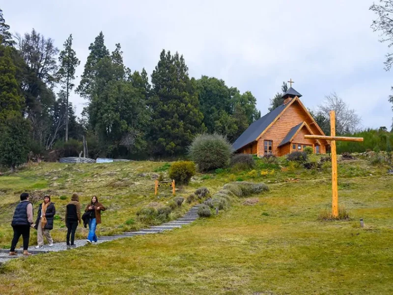 Capilla de madera Nuestra Señora de Traful entre árboles y una cruz de madera, en Villa Traful, Neuquén