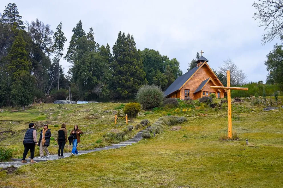 Capilla de madera Nuestra Señora de Traful entre árboles y una cruz de madera, en Villa Traful, Neuquén
