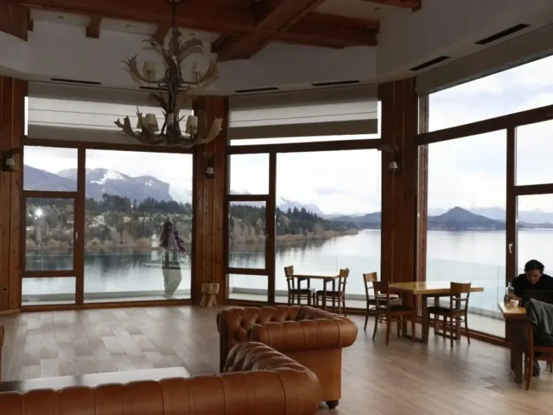 Salón del hotel Charming en Bariloche con ventanales frente al lago Nahuel Huapi