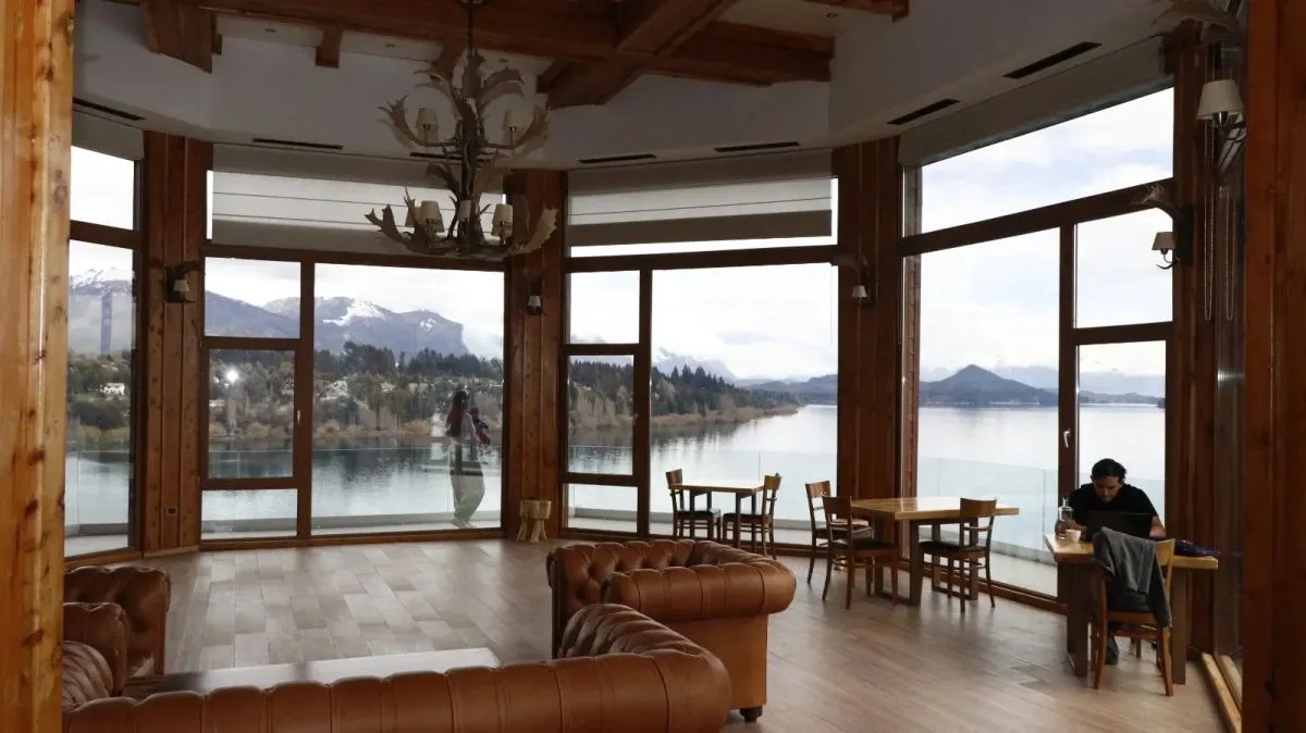 Salón del hotel Charming en Bariloche con ventanales frente al lago Nahuel Huapi