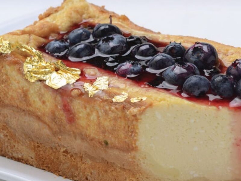 Porción de cheesecake tibio con masa de miel, salsa de calafate y frutos azules por encima