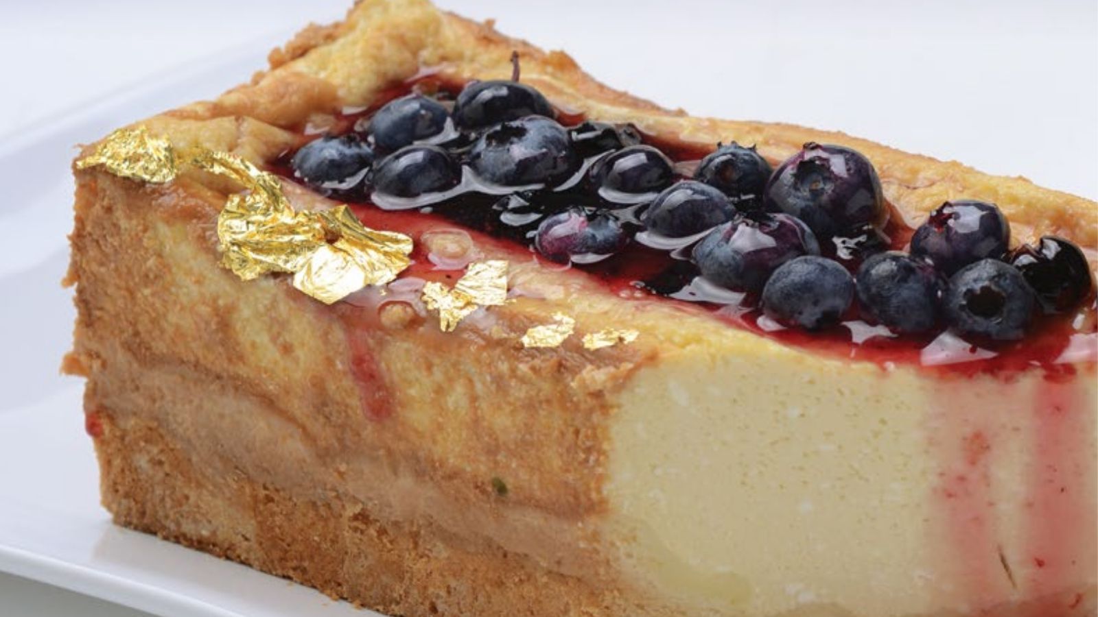 Porción de cheesecake tibio con masa de miel, salsa de calafate y frutos azules por encima