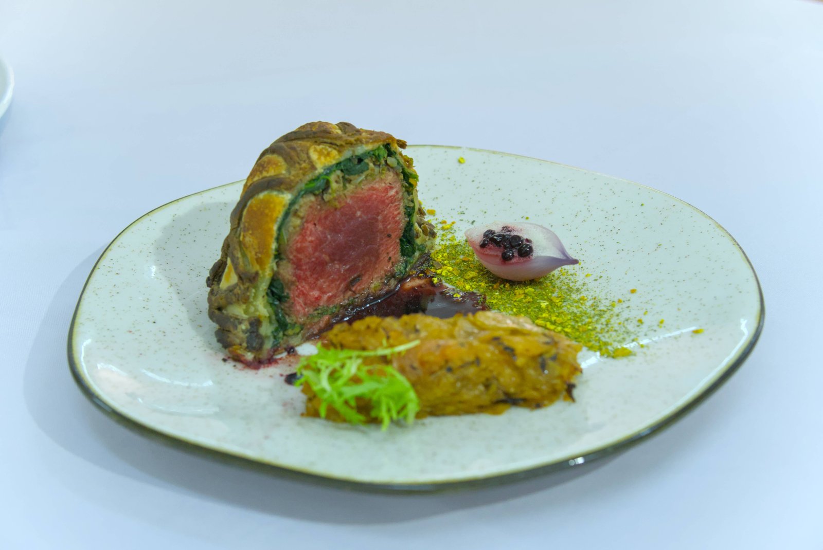 Lomo envuelto en masa con verduras y salsa de frutos rojos, plato de competencia culinaria en CocinARTE