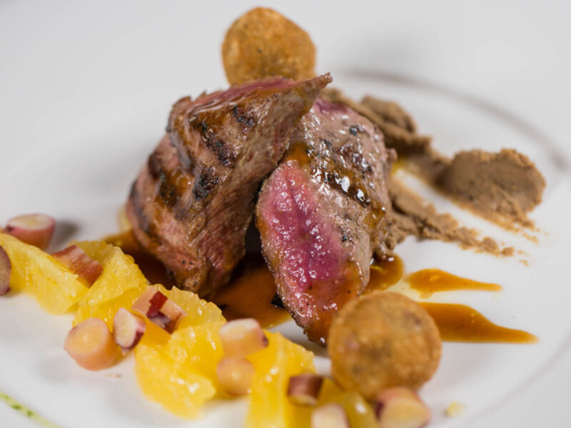 Plato de carne con cítricos y crocantes en Saurus, el restaurante de Bodega Familia Schroeder