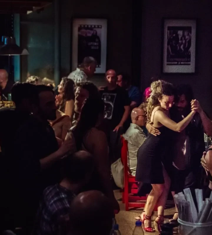 Parejas bailando tango en una milonga a media luz, propuesta del Festival Muy Tango que llega a Bariloche