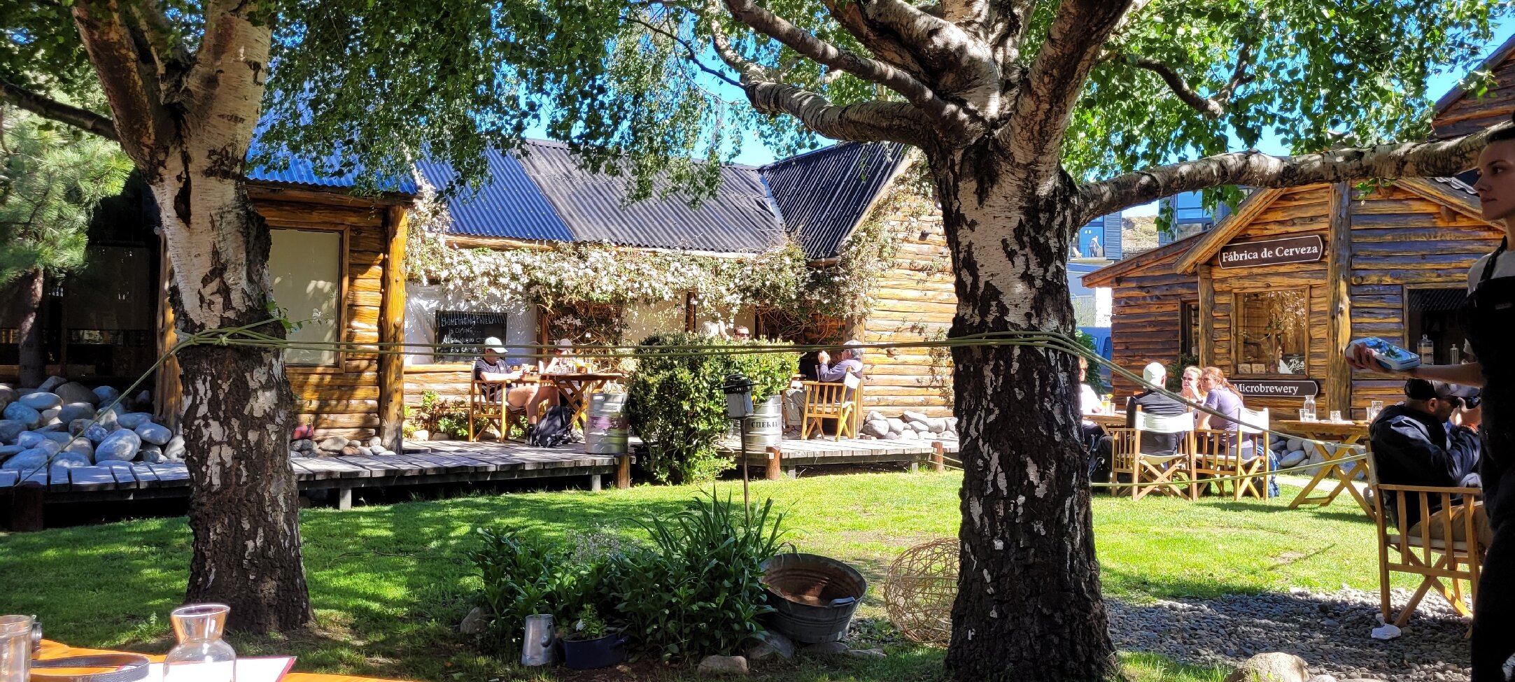 Patio con árboles y mesas al aire libre en La Cervecería