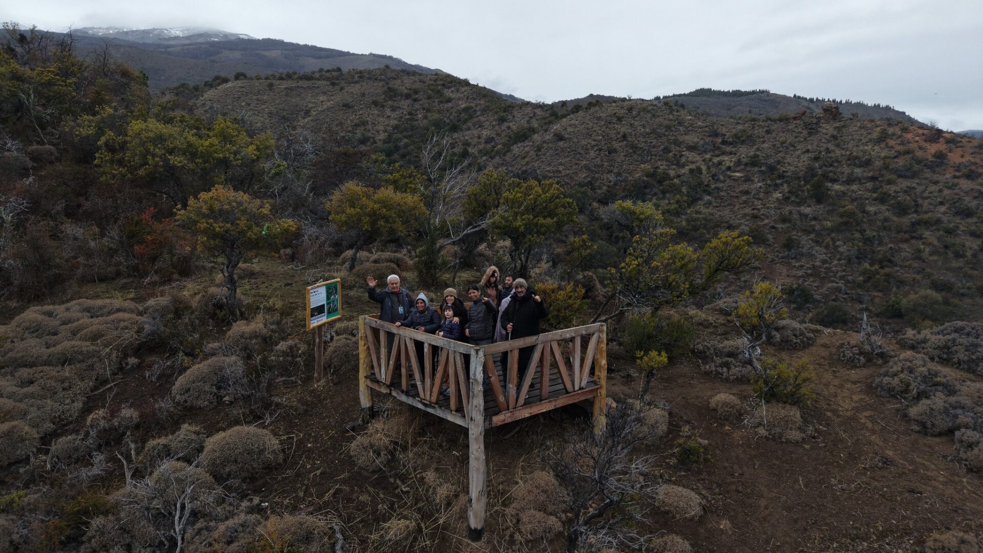 Grupo de visitantes en un mirador de madera entre los cerros y el bosque de Sierra Colorada, cerca de Lago Rosario, Trevelin