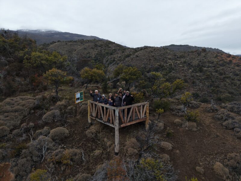 Grupo de visitantes en un mirador de madera entre los cerros y el bosque de Sierra Colorada, cerca de Lago Rosario, Trevelin