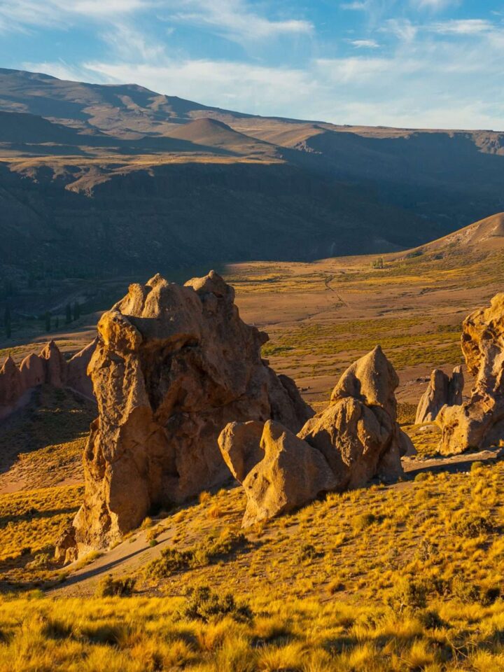 Formaciones rocosas de Los Bolillos sobre la estepa dorada de Varvarco, con la cordillera del norte neuquino de fondo