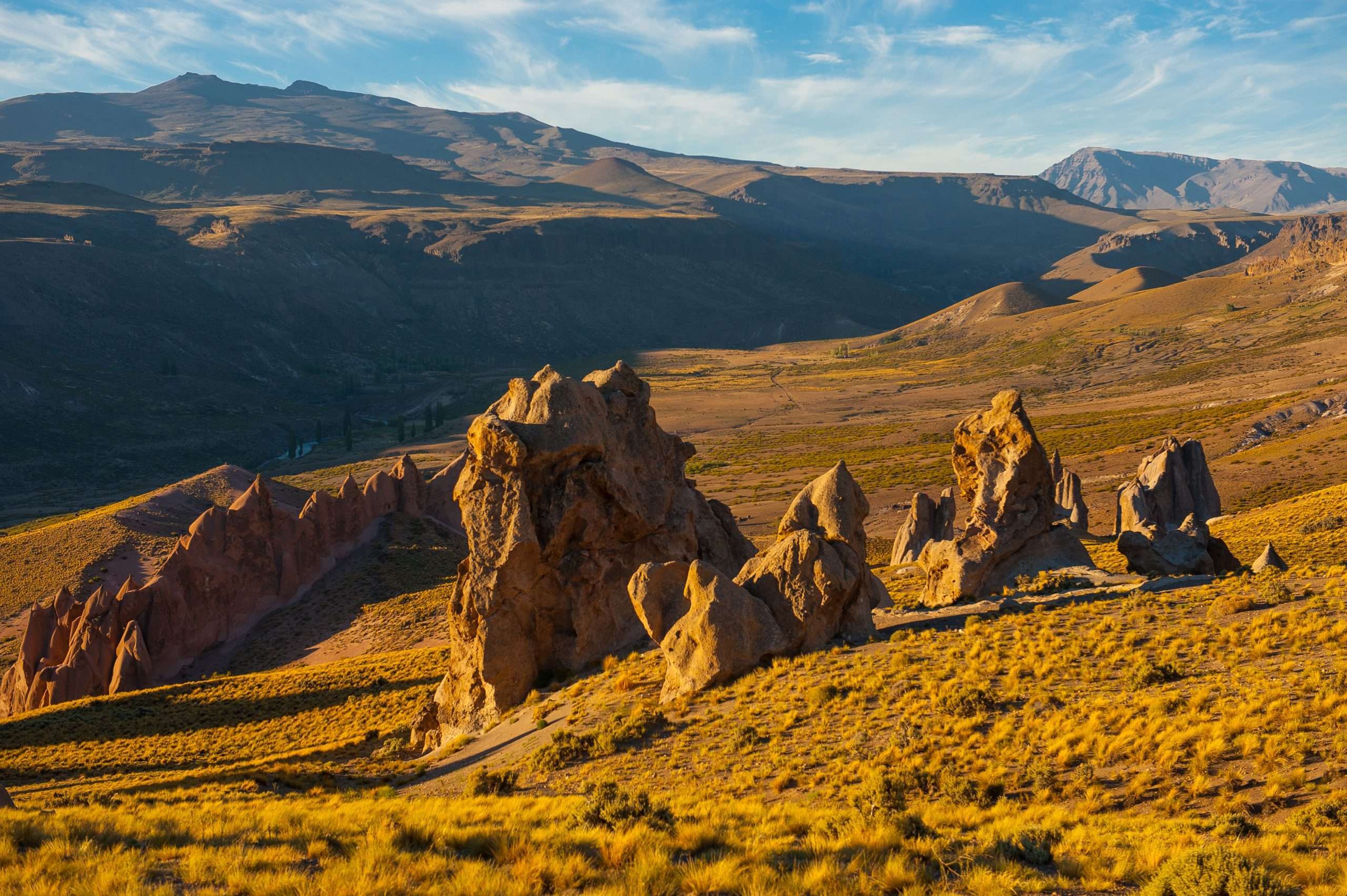Formaciones rocosas de Los Bolillos sobre la estepa dorada de Varvarco, con la cordillera del norte neuquino de fondo