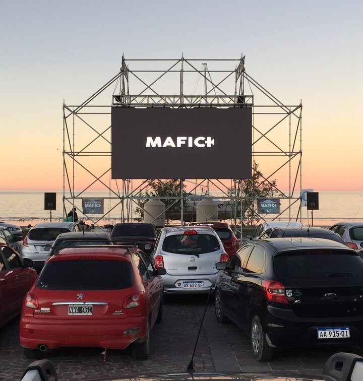 Autocine del Festival Internacional de Cine de Puerto Madryn frente al mar, con la pantalla del MAFICI y el muelle al atardecer