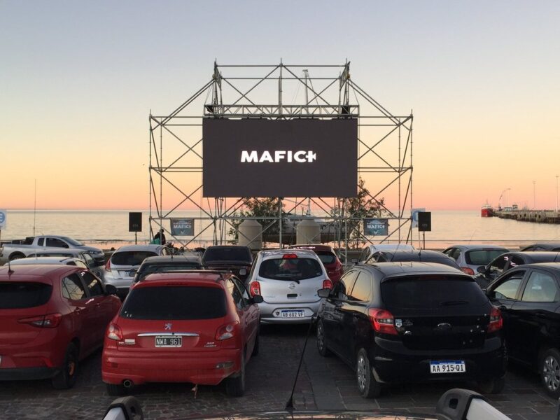 Autocine del Festival Internacional de Cine de Puerto Madryn frente al mar, con la pantalla del MAFICI y el muelle al atardecer