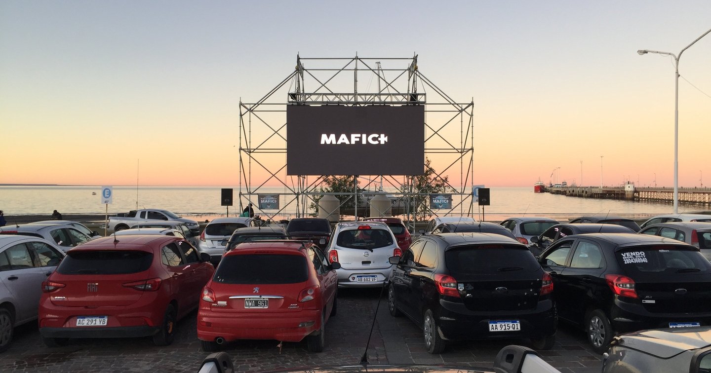 Autocine del Festival Internacional de Cine de Puerto Madryn frente al mar, con la pantalla del MAFICI y el muelle al atardecer