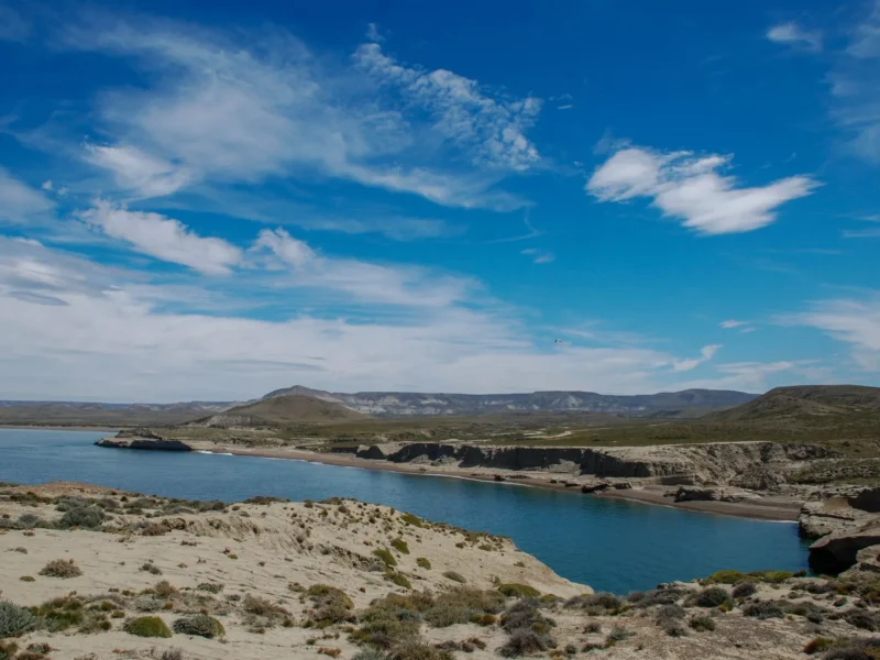 Bahía de aguas azules, playa y acantilados del Parque Nacional Monte León con la estepa santacruceña de fondo