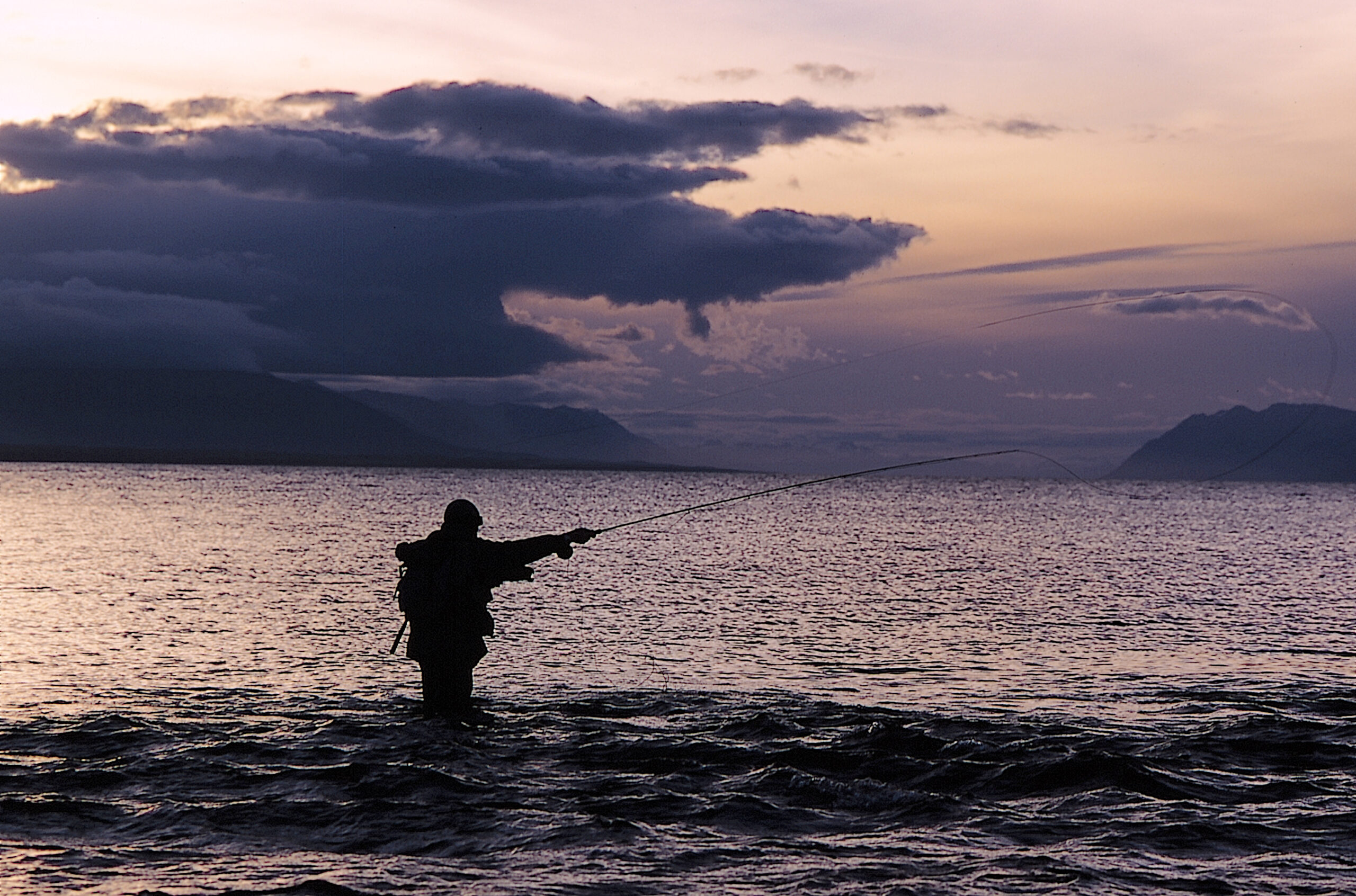 Pescador con caña de mosca al atardecer en un río de Tierra del Fuego