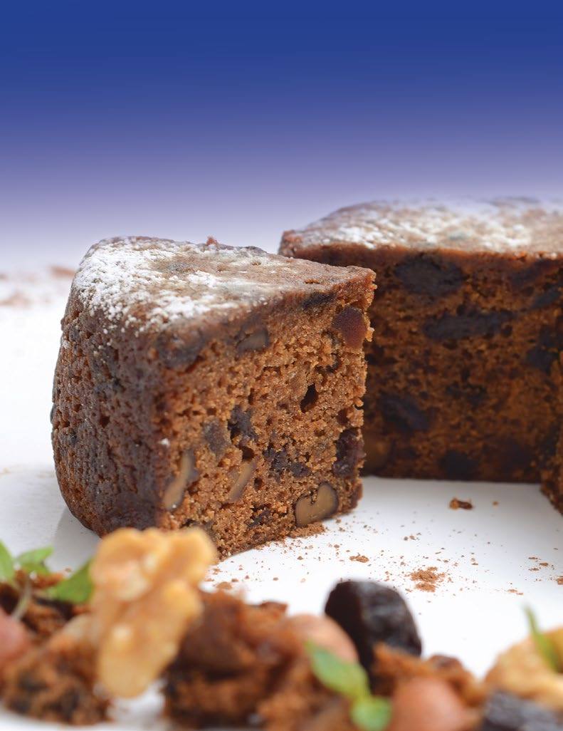 Porción de torta galesa sobre plato blanco con nueces y frutas secas
