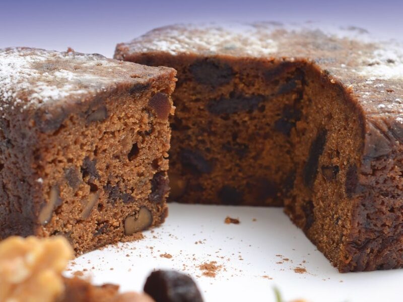 Torta galesa cortada, húmeda y oscura, con nueces, pasas y azúcar impalpable