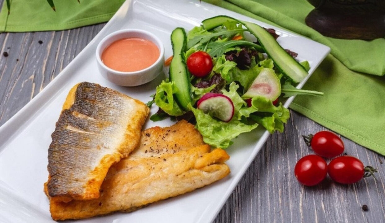 Filetes de trucha neuquina dorados a la sartén, con la piel crocante, servidos con ensalada fresca