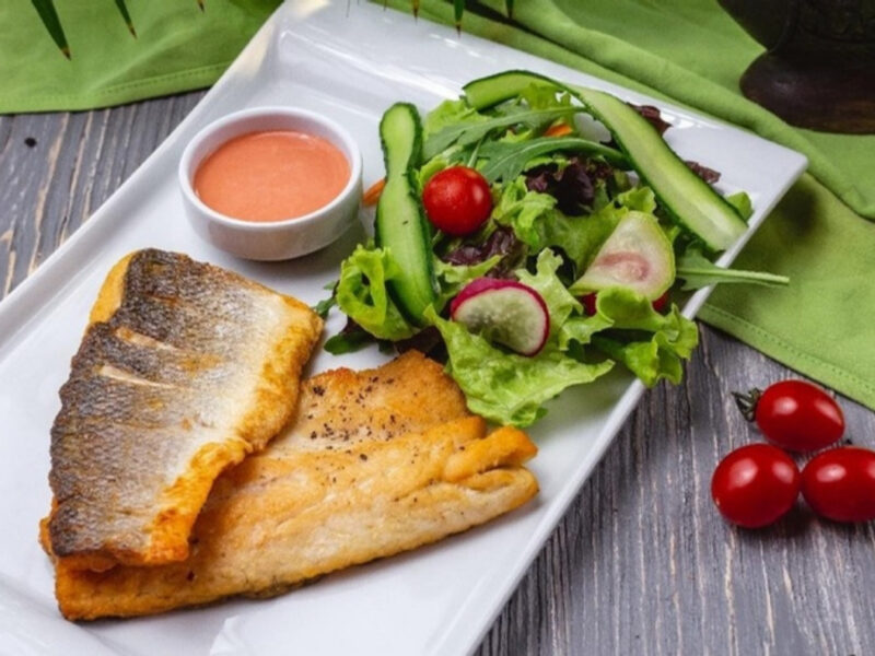 Filetes de trucha neuquina dorados a la sartén, con la piel crocante, servidos con ensalada fresca