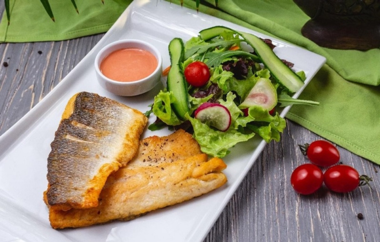 Filetes de trucha neuquina dorados a la sartén, con la piel crocante, servidos con ensalada fresca