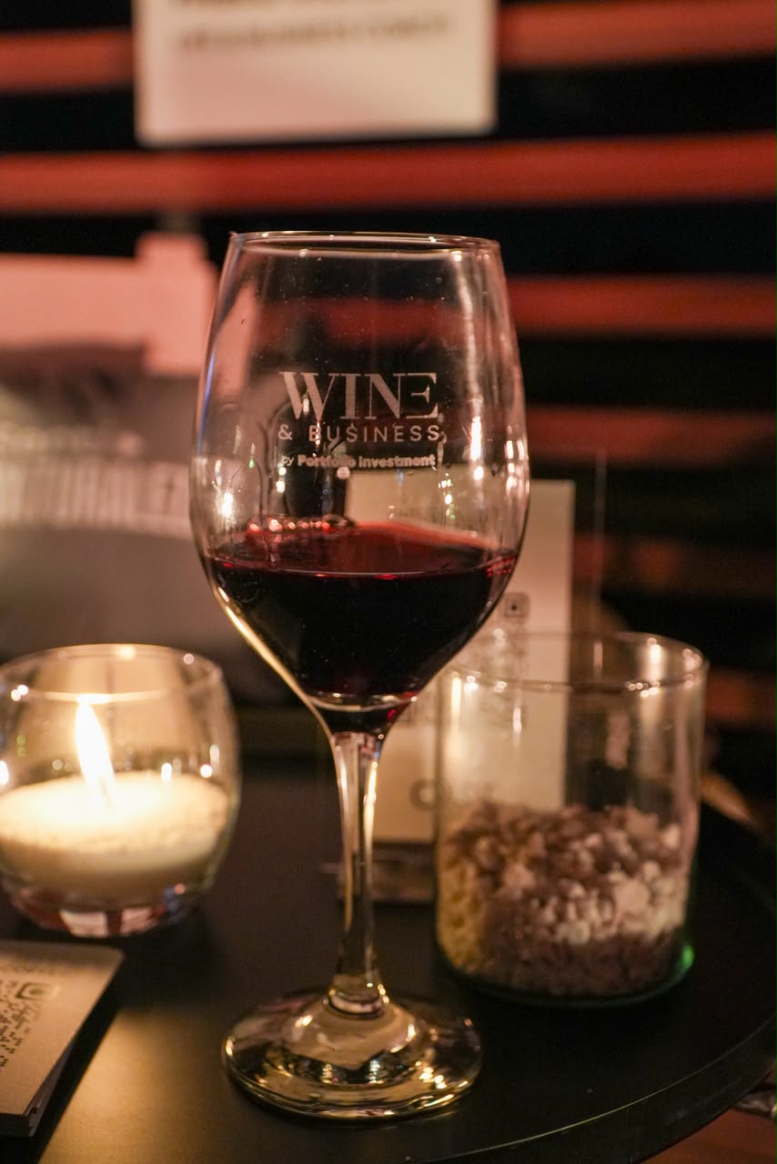 Copa de vino tinto de Wine & Business junto a una vela